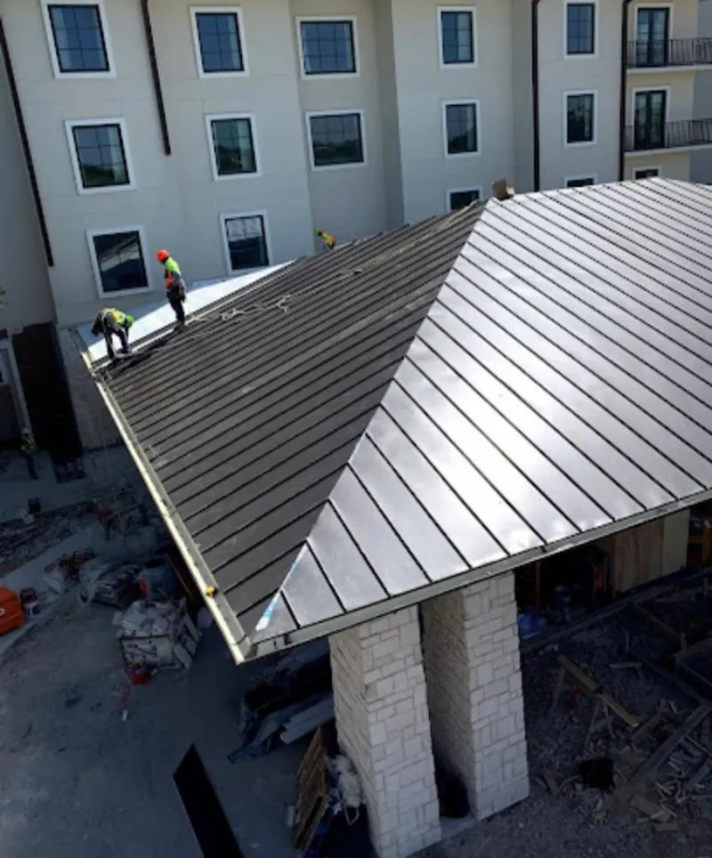 Crew installing standing seam metal roof panels on a commercial project in Ballenger Creek